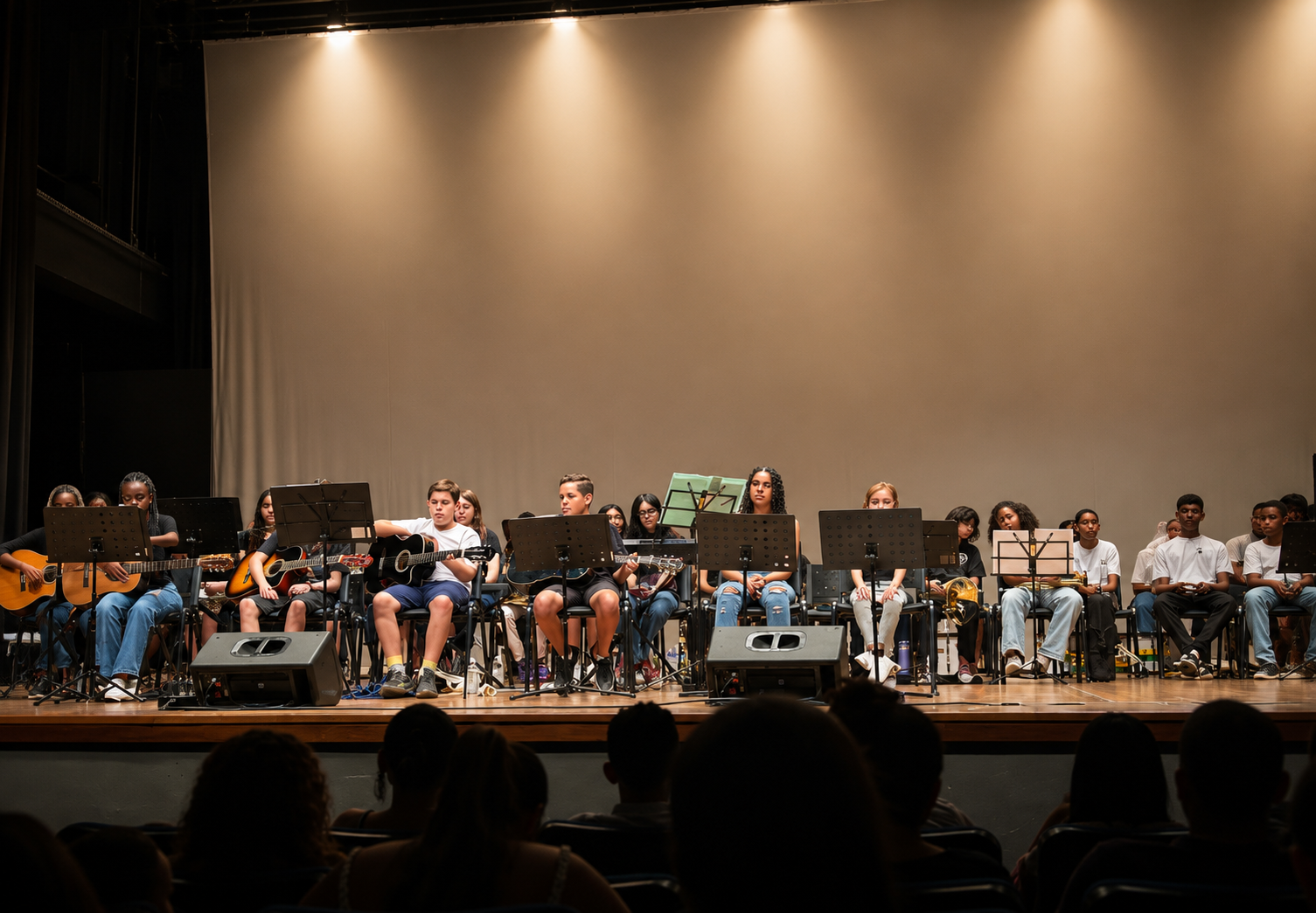 Apresentação coletiva em palco com alunos e músicos.